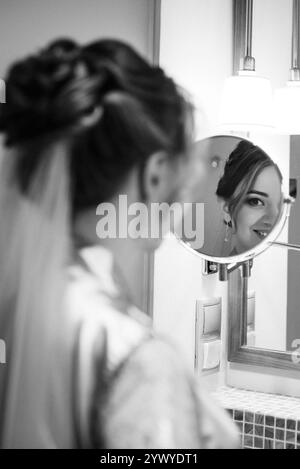 Die Braut im Schleier mit Make-up malt ihre Lippen im Badezimmer Stockfoto