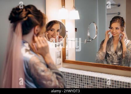 Die Braut im Schleier mit Make-up malt ihre Lippen im Badezimmer Stockfoto