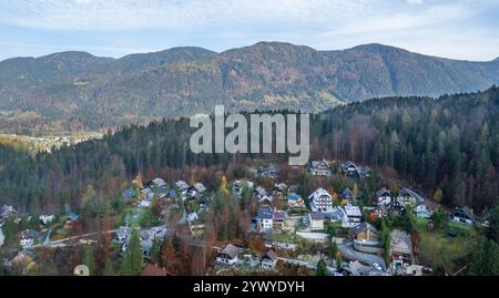 Charmante Dorfhäuser eingebettet in farbenfrohe Herbstlaub, umgeben von majestätischen Bergen und üppigen Kiefernwäldern, schaffen eine malerische Alpen Stockfoto