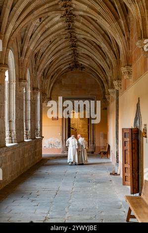 Salamanca, Spanien; 28. August 2024: Zwei Brüder in weißen Gewändern gehen durch eine Galerie im Innenhof des Klosters San Esteban Stockfoto