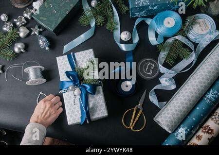 Schöner weihnachtlicher Hintergrund flach liegend mit Geschenken auf schwarz mit blauen Bändern und Tannenzweigen Stockfoto