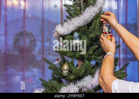 Dekoration des Weihnachtsbaums mit festlichen Ornamenten und Lametta in gemütlicher Inneneinrichtung während der Weihnachtszeit. Schweden. Stockfoto