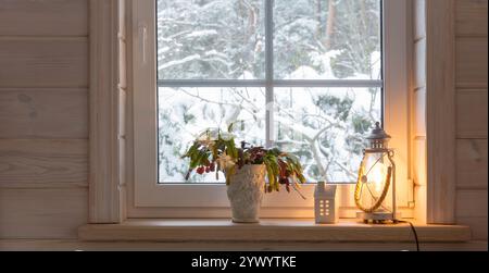 Laterne auf der Fensterbank, winterliche Schneelandschaft vor dem Fenster. Stockfoto