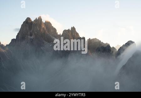 Zerklüftete Bergkette in den Dolomiten bei Tre Cime. Abendlicht trifft auf die scharfen Kalksteingipfel, während Nebel über den Kamm rollt Stockfoto