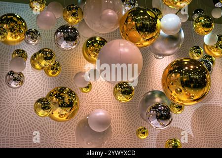 Viele verschiedenfarbige Kugeln (Gold, Silber, weiß) hängen von der Decke. Innenarchitektur. Stockfoto
