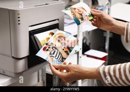 Frau mit bunten Fotos in der Nähe eines modernen Druckers drinnen, Nahaufnahme Stockfoto