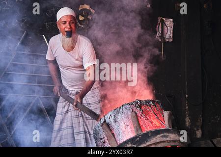 In einer Werft in Bangladesch beschäftigt sich ein erfahrener Handwerker mit umfangreicher Erfahrung geschickt mit der Herstellung von Schiffspropellern. Seine erfahrenen Hände klagen Stockfoto