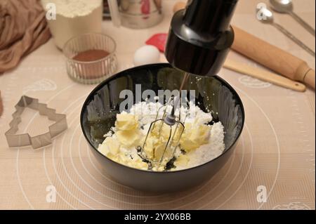 Hausgemachtes Weihnachtsgebäck, Zutaten zum Backen von Lebkuchen, Mischen von Zuckerpulver und Butter in einer schwarzen Schüssel Stockfoto
