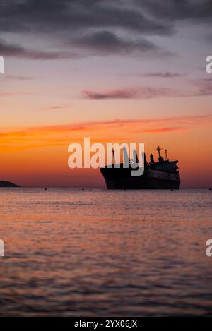 Silhouette eines Schiffes bei Sonnenuntergang über ruhigen Gewässern Stockfoto