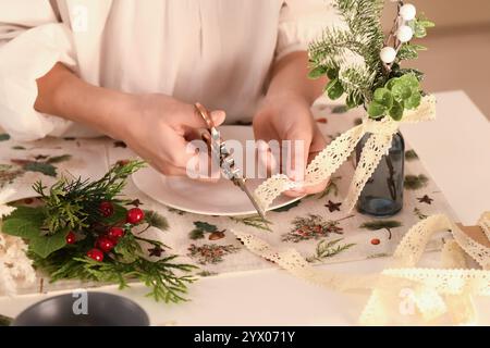 Ein Mann in leichter Kleidung sitzt an einem Tisch, der mit einer Tischdecke mit Neujahrsmuster bedeckt ist. Verschiedene dekorative Elemente sind auf dem Tisch angeordnet: Chris Stockfoto