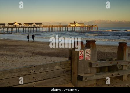 Southwold, Suffolk, England, Großbritannien - Ein Paar spaziert am Southwold Beach bei Sonnenuntergang zwischen Pier und Groyne, ohne Schwimmen und ohne Kletterschilder Stockfoto