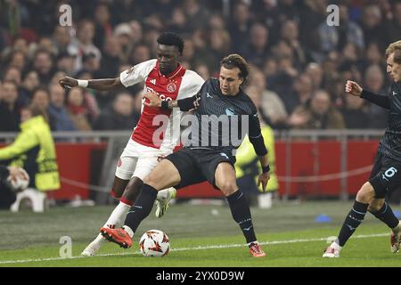 AMSTERDAM - (l-r) Bertrand Traore von Ajax, Luca Pellegrini von SS Lazio, Nicolo Ravella von SS Lazio während des UEFA Europa League Spiels zwischen AFC Ajax Amsterdam und SS Lazio Roma in der Johan Cruijff Arena am 12. Dezember 2024 in Amsterdam, Niederlande. ANP | Hollandse Hoogte | MAURICE VAN STEEN Credit: ANP/Alamy Live News Stockfoto