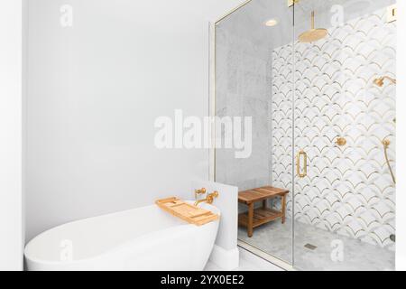 Badezimmer mit freistehender Badewanne mit goldenem Wasserhahn und Dusche mit Mosaik-Marmor und Goldfliesen, goldenen Wasserhähnen und gemusterten Fliesenböden Stockfoto