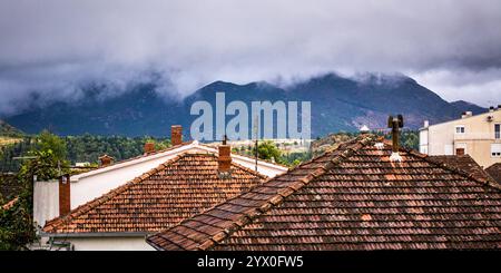 Dächer mit rauchenden Schornsteinen und nebligen Hügeln in den Rücken. Stockfoto