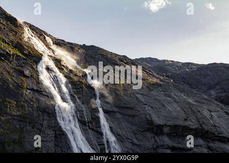 Eine Nahaufnahme eines Wasserfalls, bei dem das kaskadierende Wasser gegen die zerklüfteten Felsen darunter stürzt. Die schiere Kraft des Wassers wird beim Spritzen deutlich Stockfoto