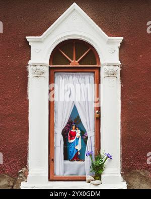 Abbildung der Heiligen Maria mit Jesuskind in einem Schrein in der Wand. Stockfoto