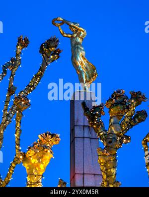 Das Kriegsdenkmal Gëlle Fra (Goldene Dame) auf dem Place de la Constitution in Luxemburg-Stadt, Luxemburg, steht während der Zeit zwischen festlich geschmückten Bäumen Stockfoto