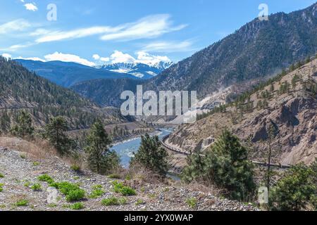 An einem heißen Sommertag fährt der Güterzug langsam entlang des Fraser River im Fraser Canyon bei Lillooet, British Columbia. Blick von oben. Stockfoto