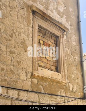 Korcula, Kroatien - 30. Juni 2024: Nahaufnahme, altes Fenster gefüllt mit Ziegeln am Kanavelic-Turm Stockfoto