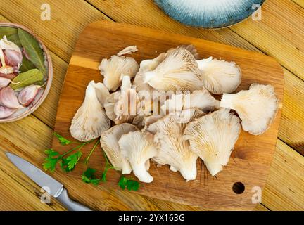 Es gibt einen Haufen roher Austernpilze auf dem Schneidebrett. Stockfoto