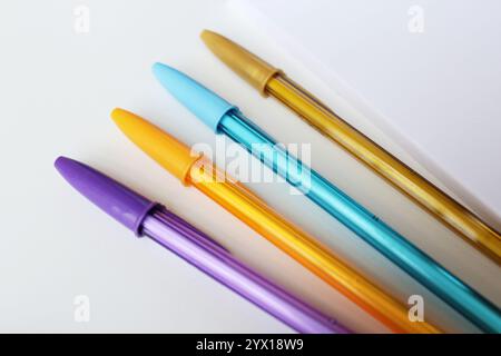 Vier bunte Stifte, die diagonal auf weißem Hintergrund nebeneinander angeordnet sind. Farbige Schreibwaren, Schulbedarf, Kunstunterricht, Kreativitätskonzept. Stockfoto