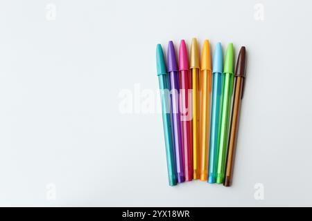 Bunte Stifte nebeneinander auf weißem Hintergrund angeordnet. Farbverlauf mit Kugelschreiber. Schreibwaren, Schulbedarf, Kreativkonzept. Stockfoto