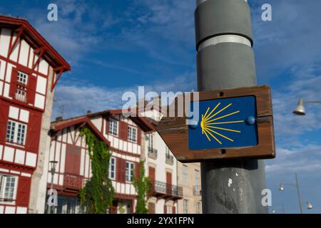 Typischer Wegweiser entlang des Voie du Littoral im Dorf Ciboure, Frankreich. Die Jakobsmuschel und der gelbe Pfeil sind allgegenwärtige Symbole des Camin Stockfoto