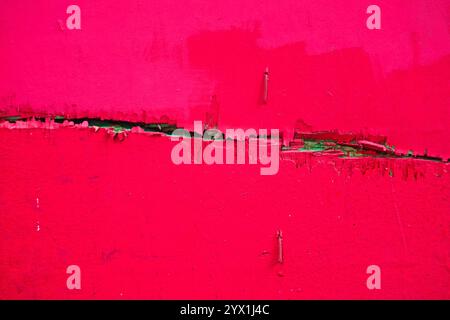 Leuchtend rote, abziehbare Farbstruktur mit grünen Rissdetails auf Holzoberfläche Stockfoto