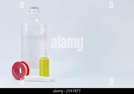 Medizinische Verbrauchsmaterialien einschließlich Tropfwasserflasche, antiseptischer Tropf, Band und Bandage auf weißem Hintergrund Stockfoto