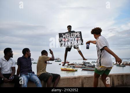 Sansibar, Tansania. Dezember 2024. Ein Mann posiert für Fotos, während er am 10. Dezember 2024 in der Steinstadt Sansibar in Tansania ins Meer taucht. Stone Town, das 2000 von der Organisation der Vereinten Nationen für Bildung, Wissenschaft und Kultur zum Weltkulturerbe erklärt wurde, ist ein Paradebeispiel für die Handelsstädte an der Küste Swahili in Ostafrika. Das städtische Gefüge und die Stadtansicht sind weitgehend intakt. Viele schöne Gebäude spiegeln eine einzigartige Kultur wider, die afrikanische, arabische, indische und europäische Einflüsse vereint, die sich über mehr als ein Jahrtausend angesammelt haben. Quelle: Han Xu/Xinhua/Alamy Live News Stockfoto