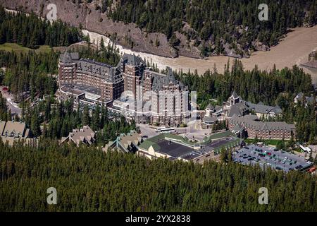 Ein großes Hotel mit vielen Bäumen im Hintergrund. Das Hotel ist von einem Wald umgeben und hat einen Fluss, der durch ihn fließt Stockfoto