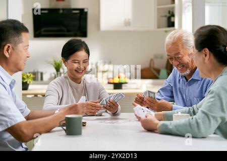 Gruppe glücklicher asiatischer Senioren, zwei Paare, die zu Hause zusammen Karten spielen Stockfoto