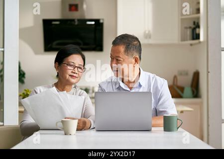 Ein älteres asiatisches Paar, das zu Hause am Tisch sitzt und mit einem Laptop einen Finanzplan erstellt Stockfoto