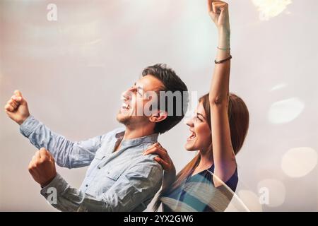 Junges Paar feiert zusammen, hebt die Arme in freudiger Begeisterung, strahlt Glück und Positivität aus. Ihre ekstatischen Ausdrücke erfassen die essener Stockfoto