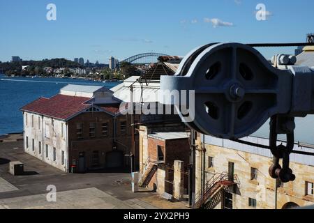 Pulley und Industriegebäude auf Cockatoo Island mit Blick auf die Sydney Harbour Bridge, Sydney, Australien Stockfoto