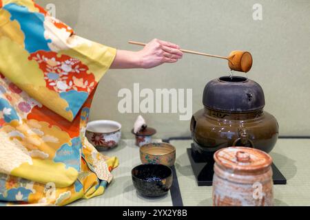 Eine Frau in gelbem Kimono beginnt mit der Teezeremonie. Stockfoto