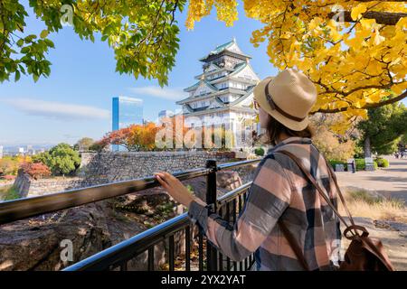 Glückliche Touristen haben Spaß vor der Burg Osaka, umgeben von Herbstlaub. Konzept der Freiheit und der Reise nach Asien. Unscharfer Hintergrund. Osaka Castle ist Stockfoto