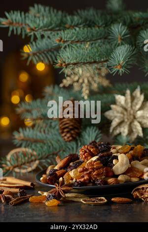 Weihnachtliche Gewürze, verschiedene Nüsse, Rosinen und trockene Zitrusscheiben auf einem Küchentisch. Weihnachtliches Stillleben mit Fichtenzweigen und getrockneten Früchten. Im Stockfoto