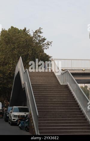 Treppen zu einem Brückenweg entlang einer Allee, mit Bäumen und Autos im Hintergrund, Wohngebiet von Xi'an, China Stockfoto