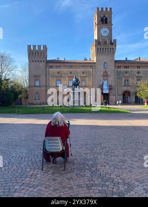 Busseto, Parma, Italien - 23. November 2024 eine ältere Frau sitzt und betrachtet die Statue von giuseppe verdi und die prachtvolle Villa pallavicino in Stockfoto