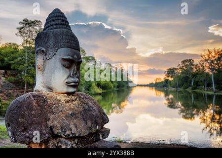 Stein Asura und Sonnenuntergang über dem Graben um Angkor, Kambodscha Stockfoto