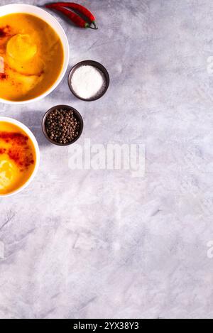 Zwei Schüsseln mit Kürbissuppe mit Chili-Pfeffer und Creme auf weißem Tisch. Flache Ladefläche mit Kopierraum. Cremesuppe. Konzept der leckeren gesunden Ernährung. Stockfoto