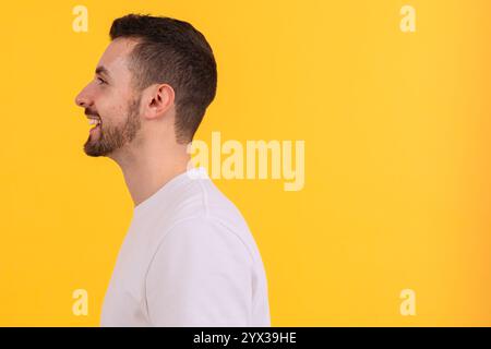 Seitenprofil eines lächelnden Mannes in einem weißen T-Shirt auf gelbem Hintergrund Stockfoto
