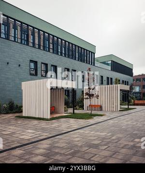 Modernes 3-stöckiges Bürogebäude. Innenhof des modernen Business Centers mit blauen Wänden, zwei Raucherkabinen im Freien in der Nähe. Stockfoto