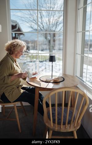 Eine Frau mittleren Alters, die Bericht liest und Kaffee trinkt. Stockfoto