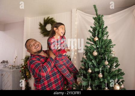 Vater und Tochter lachen vor dem weihnachtsbaum Stockfoto