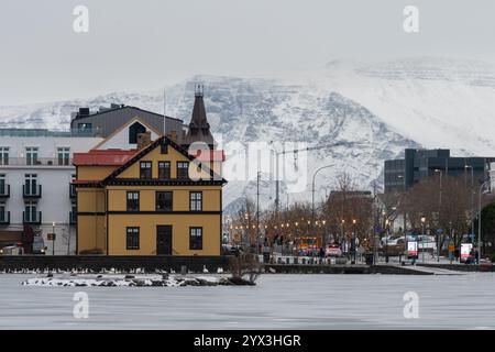 Blick auf das Zentrum von Reykjavik vom gefrorenen See, Tjornin, im Winter. Wunderschönes isländisches Stadtbild. Stockfoto