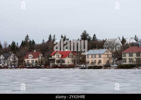 Blick auf die Häuser in Reykjavik vom gefrorenen See, Tjornin, im Winter. Wunderschönes isländisches Stadtbild. Stockfoto