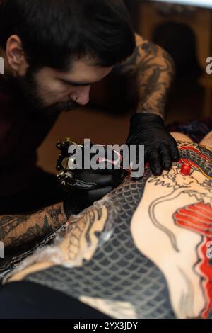 Ein Tätowierer macht ein Tattoo für einen Klienten im Studio Stockfoto