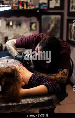 Ein Tätowierer macht ein Tattoo für einen Klienten im Studio Stockfoto
